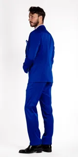 Traje de vestir compuesto por chaqueta y pantalón en color azul cobalto. La chaqueta presenta solapas en punta de raso al tono, cierre de un botón y bolsillos de doble vivo. El pantalón es de corte recto y diseño formal.