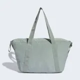 Bolso deportivo Adidas de diseño minimalista en color gris, con correas de hombro integradas y correa ajustable extraíble. Cuenta con un bolsillo frontal con cierre y logo de la marca estampado en tono sobre tono.