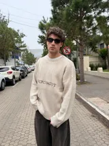 Sweater de tejido acanalado en color beige, con corte semi oversize, cuello redondo y logo bordado en el pecho.