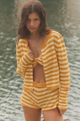Chaqueta corta de punto a rayas horizontales en tonos naranja y amarillo, con cuello redondo, manga larga y cierre frontal de botones.