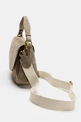 Bolso bandolera de piel gamuzada color gris topo, con solapa curva, asa de mano corta y herrajes metálicos dorados.