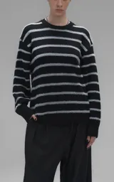 Sweater de cuello redondo con diseño de rayas horizontales en negro y gris. Presenta una textura suave y peluda, con terminaciones en punto rib en el cuello.