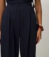 Pantalón largo femenino texturizado color azul marino, modelo aladim, con volumen amplio en las piernas y estrechamiento en el ruedo. Posee cintura elástica incorporada y pliegues delanteros.
