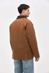 Campera de gabardina color marrón con cuello de pana en tono oscuro. Presenta cierre frontal con botones a presión, bolsillos laterales con solapa y diseño de calce clásico.
