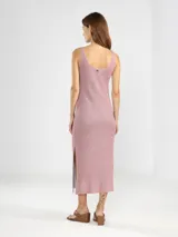 Vestido midi sin mangas, confeccionado en punto jersey con hilo Lurex que aporta un brillo sutil. Presenta escote bote redondeado y aberturas laterales en el ruedo.