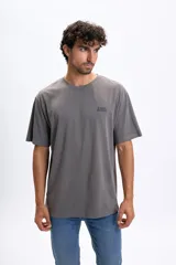 Remera oversize de manga corta color gris oscuro, con cuello redondo y estampado frontal con la frase "JUNGLE BUNGLE" en negro.