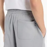 Pantalón de jogging gris de felpa perchada con ajuste holgado. Cuenta con cordón regulable, cintura y bajos elásticos, bolsillos laterales y trasero, y logo de New Balance estampado en el muslo izquierdo.