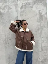 Campera tipo gamulán color marrón, con interior y detalles en corderito blanco. Presenta cierre frontal, cuello solapa y bolsillos laterales.