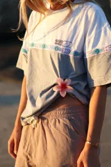 Remerón gris con mangas cortas y estampado frontal con el logo de la marca 'Glassy Waves' y un diseño de ondas y motivos tribales.