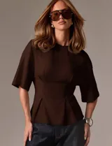 Remera marrón de diseño estructurado con silueta entallada, mangas amplias y detalles de pinzas frontales que aportan forma y volumen en la cintura.