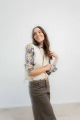 Chaleco tejido en lana merino, de color crudo, con cuello redondo y diseño clásico sin mangas.