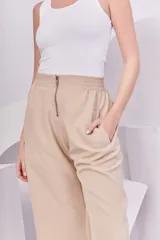 Pantalón recto color beige con cintura elástica y cierre metálico.