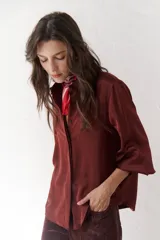 Camisa azul marino de satén con cuello clásico, cierre frontal con botones y mangas largas con puños abotonados.