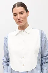 Camisa de manga larga celeste a rayas con pechera blanca lisa en el frente, cuello camisero y botones frontales.