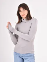 Polera de punto color gris claro, de corte al cuerpo y manga larga, con cuello alto vuelto.