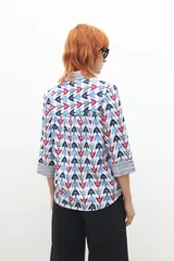 Blusa de manga larga con cuello camisero y estampado con motivos geométricos en tonos azul, rojo y blanco.