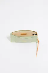 Monedero Bimba y Lola de piel vacuna con textura granulada, color verde menta. Presenta cierre con cremallera, tirador de cordón en color naranja, tarjetero exterior y logo de la marca grabado en dorado.