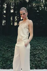 Pantalón de tiro alto confeccionado en tejido satinado, con cintura elástica y bolsillos laterales. Presenta un diseño de corte recto con bajo acabado en aplicación de encaje a tono.