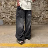 Jean de corte super baggy en color gris oscuro con efecto lavado. Presenta un diseño de pierna ancha y holgada, con bolsillos traseros amplios que incluyen bordados gráficos con texto.