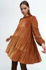 Vestido corto de terciopelo color cobre, con diseño de volados en capas, cuello redondo con detalle de volado y mangas largas con fruncidos.