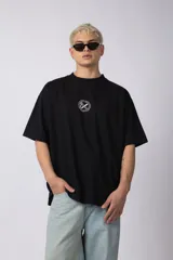 Remera oversize de algodón negro, con cuello redondo y manga corta ancha. Presenta un pequeño logo bordado en el pecho con un símbolo de prohibido fumar.