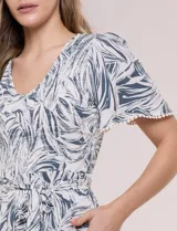 Vestido midi de rayón con estampado de hojas en tonos verde oscuro y blanco. Cuenta con escote en V, pechera fruncida con punto smock, mangas cortas con detalles de pompones en los bordes y lazo ajustable en la cintura.