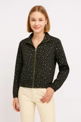 Campera verde militar con estampado animal print de leopardo en tonos grises. Tiene cuello alto, cierre frontal con cremallera, mangas largas con puños elásticos y cintura elástica.