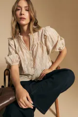 Camisa de manga corta abullonada con terminación elastizada, cuello con leve frunce y calce recto. Presenta una estampa floral integral sobre fondo claro.