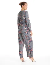 Enterito de crepe con estampado floral, escote en V, mangas largas con puños abotonados y lazo de ajuste en la cintura.