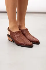 Zueco slingback negro de cuero vacuno con textura grabada geométrica, taco bloque de madera y tira ajustable con hebilla metálica.
