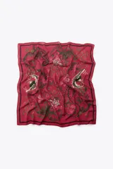 Pañuelo cuadrado de diseño fluido con estampado floral y de estilo paisley en tonos rojos, verdes y negros. Presenta un borde definido con una línea negra perimetral.