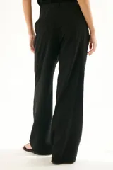 Pantalón de vestir color beige, de corte palazzo y tiro alto. Incluye cinturón de cadena plateada.