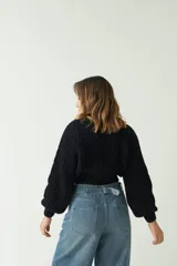 Sweater tejido de punto grueso color crema, con textura chunky, corte cropped, mangas abullonadas y puños ajustados.