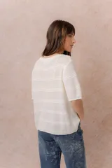 Sweater tejido celeste de manga corta con textura y delicadas líneas horizontales en relieve. Presenta cuello redondo y calce amplio con hombros caídos.