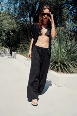 Pantalón de tiro medio con cintura elástica y pierna ancha. Presenta bolsillos laterales ocultos en la costura y un diseño fluido.