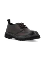 Zapato acordonado de cuero con acabado envejecido, diseño de puntera reforzada y suela track dentada con costura decorativa en contraste.