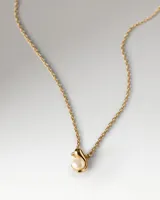 Collar Pdpaola modelo La Perla, de cadena fina dorada con un dije colgante de perla con detalle de metal.