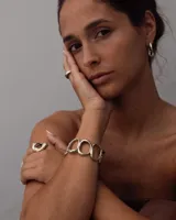 Brazalete rígido de diseño orgánico, compuesto por eslabones irregulares unidos entre sí, con acabado metálico brillante.