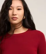 Suéter ajustado de punto color crema, con cuello redondo y mangas largas con botones metálicos en los puños. Confeccionado con viscosa sostenible.