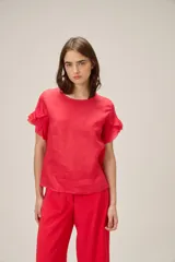 Blusa de lino color rosado, de corte recto y holgado, con cuello redondo y mangas cortas adornadas con volados.