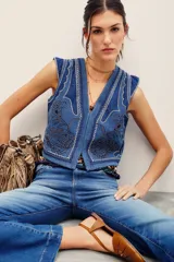 Chaleco de denim azul de corte ajustado, con cuello en V y elaborados bordados decorativos en contraste.