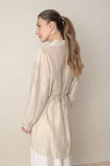 Camisa larga italiana color crudo, de calce holgado, con lazo en la cintura con flor y mangas largas con presilla para sujetar.