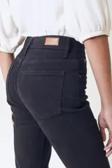 Pantalón jean negro de corte flare, tiro alto y largo cropped con terminación desflecada.