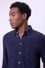Camisa azul marino de manga larga con cuello abotonado y bolsillo en el pecho.