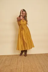 Vestido midi sin mangas de color mostaza, con escote en V cruzado y un lazo ajustable en la cintura.