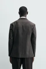 Blazer de corte relajado confeccionada en tejido de lana. Presenta cuello con solapa de muesca, cierre frontal de un botón, bolsillos plastrón en la cadera y manga larga con puños abotonados.