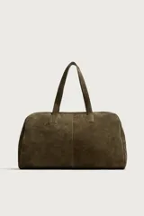 Bolso de viaje de diseño minimalista confeccionado en piel con acabado serraje. Cuenta con compartimento principal con cierre de cremallera e imanes, interior con bolsillos organizadores y doble asa de mano en piel.