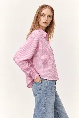 Camisa de manga larga con diseño de rayas verticales en tonos rosado y blanco, corte holgado y bolsillos frontales con solapa en el pecho.