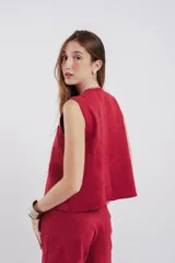 Chaleco de gamuza negro, con diseño abierto, cierre de un solo botón en la parte superior y dos bolsillos frontales.