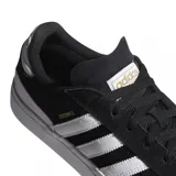 Championes adidas Busenitz Vulc II de estilo skate, confeccionados en gamuza negra con las icónicas tres tiras laterales en blanco. Presentan una suela vulcanizada blanca, refuerzo en el talón y el nombre del modelo en dorado en el lateral.